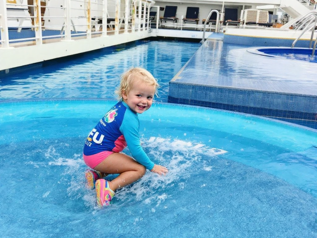 toddler-in-water-shoes-and-uv-rash-guard-playing-in-shallow-1778079771.png